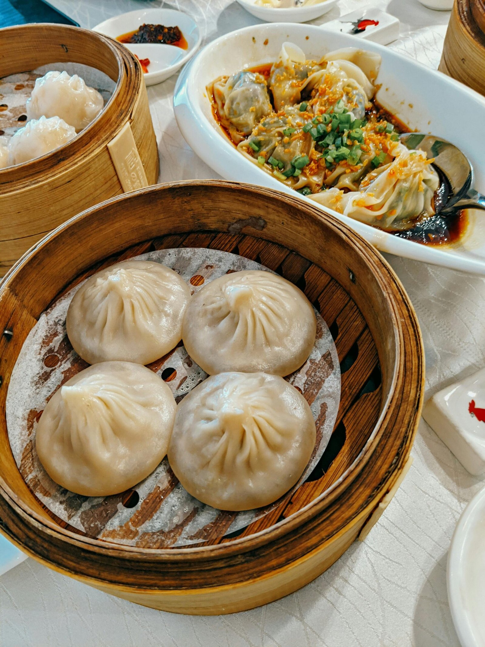 Close-up of steamed dumplings and bao varieties served with sauces, perfect for Asian culinary themes.